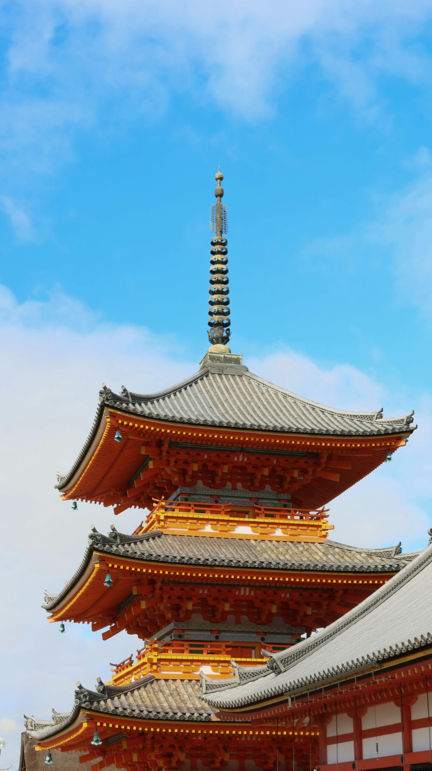 Stunning vertical shot of Kiyomizu-dera's pagoda with a blue sky backdrop, capturing the essence of Japanese architecture.